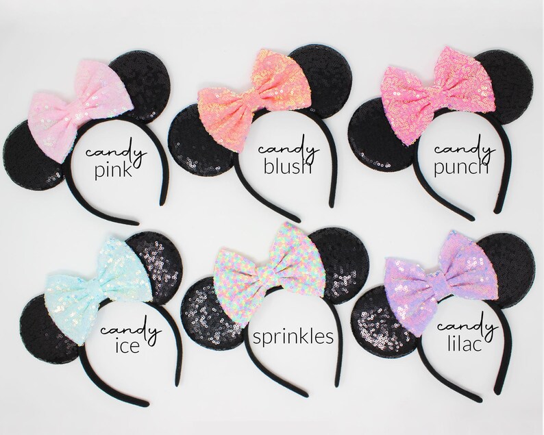 May include: Six headbands with black sequin ears and colorful sequin bows. The bows are labeled candy pink, candy blush, candy punch, candy ice, sprinkles, and candy lilac. Each headband features a thin black band and two round ears.