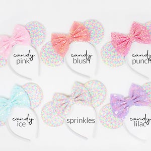May include: Six headbands with round ears covered in multicolored confetti glitter and large sequined bows. The bows are labeled candy pink, candy blush, candy punch, candy ice, sprinkles, and candy lilac, each featuring a distinct pastel color.