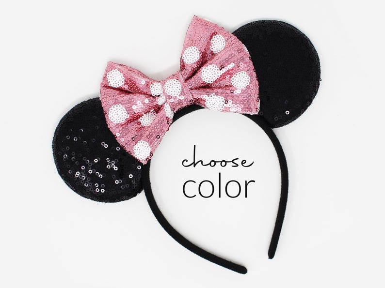 May include: A headband featuring two round black sequined ears and a large pink sequined bow with white polka dots. The center of the headband displays the text choose color in a black script and sans-serif font combination.