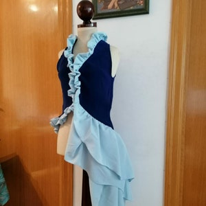 Könnte beinhalten: Eine blaue und hellblaue ärmellose Weste mit Rüschenkragen und Saum. Die Weste wird auf einem Mannequin mit einem Pferdeschwanz präsentiert.