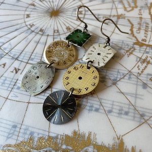 May include: Handmade earrings crafted from repurposed watch faces. The earrings display a mix of shapes, including circles and squares, with visible numbers and hands. The colour scheme includes gold, silver, and green, giving a vintage, steampunk appearance.