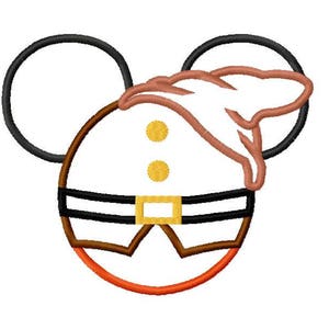 May include: A brown and orange cartoon character with large black ears and a brown hat. The character has two yellow buttons on its chest and a black belt with a gold buckle.