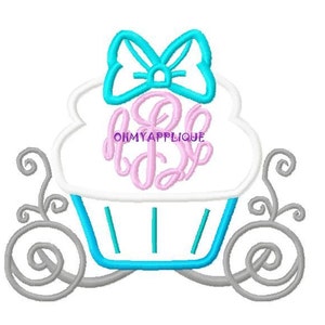 Op de afbeelding: Een witte cupcake met blauwe frosting en een turquoise strik erop. De cupcake staat in een grijze koets met een roze monogram in het midden. De tekst "OHMYAPPLIQUE" is zichtbaar op de cupcake.