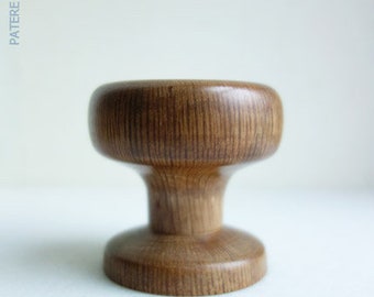 May include: A wooden knob with a rounded top and a wide base. The knob is made of light brown wood with a natural grain pattern.