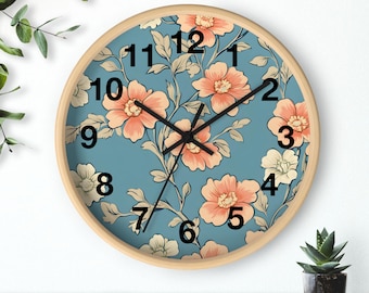 May include: Round wall clock with a light wood frame. The clock face features a teal background with a floral pattern in peach and cream. Black hands and black numerals mark the time. A decorative piece for any room.