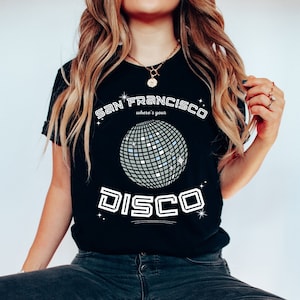 Puede incluir: Camiseta negra con un gr&aacute;fico blanco de una bola de discoteca y el texto "San Francisco where's your disco"