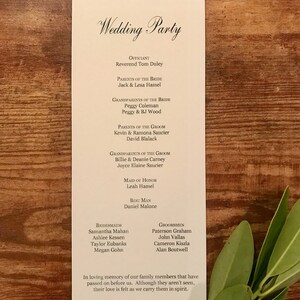 Pode incluir: Uma lista de casamento com os nomes do celebrante, dos pais da noiva e do noivo, dos av&oacute;s da noiva e do noivo, da dama de honra, do padrinho, das damas de honra e dos padrinhos. O texto na parte inferior diz: "Em mem&oacute;ria carinhosa de nossos familiares que nos precederam. Embora n&atilde;o os vejamos, sentimos o seu amor enquanto os carregamos em nossos cora&ccedil;&otilde;es."