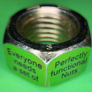 Op de afbeelding: Een groene metalen moer met de tekst "Everyone needs a set of Perfectly functional Nuts" erop gedrukt.