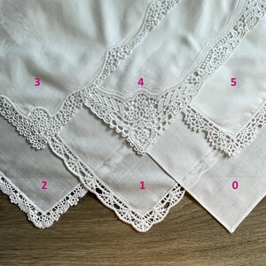 May include: Close-up of several white handkerchiefs with delicate, ornate lace edging. The handkerchiefs are arranged in a fan-like pattern, showcasing the intricate details of the lace. The lace designs vary, adding visual interest.