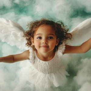 May include: A young child with curly brown hair and brown eyes, wearing a white dress and feathery wings, appears to be floating in a cloudy, teal-colored sky. The child's arms are outstretched, and she is smiling.