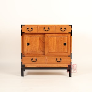 May include: A wooden cabinet with four drawers and two doors. The cabinet has black metal hardware and stands on four legs. The cabinet is made of a light brown wood.