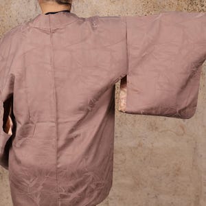 May include: A mauve-colored kimono with a subtle floral pattern. The kimono has long sleeves and a wide, open collar.