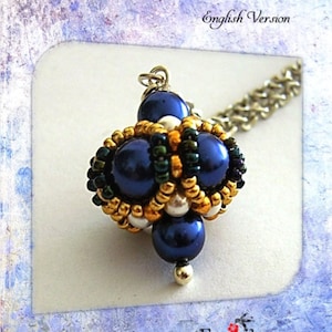 Può includere: Tutorial per un ciondolo a lanterna fatto a mano. Il ciondolo è realizzato con perline blu scuro, perline dorate e verdi e dettagli bianchi. Il testo recita "Lantern Pendant Tutorial English Version".