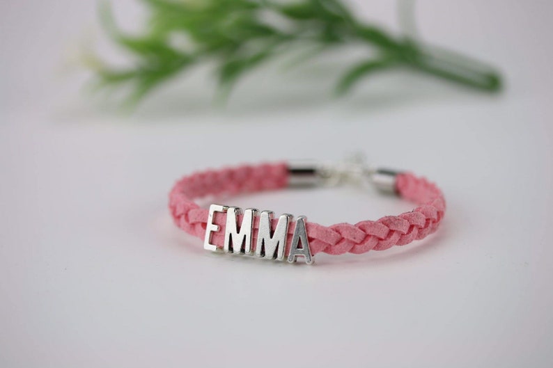 May include: A pink braided leather bracelet with a silver charm that says "EMMA".