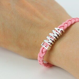 May include: A pink braided leather bracelet with a silver charm that says "EMMA".