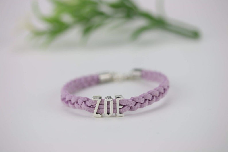 May include: A purple braided bracelet with a silver charm that says "ZOE".