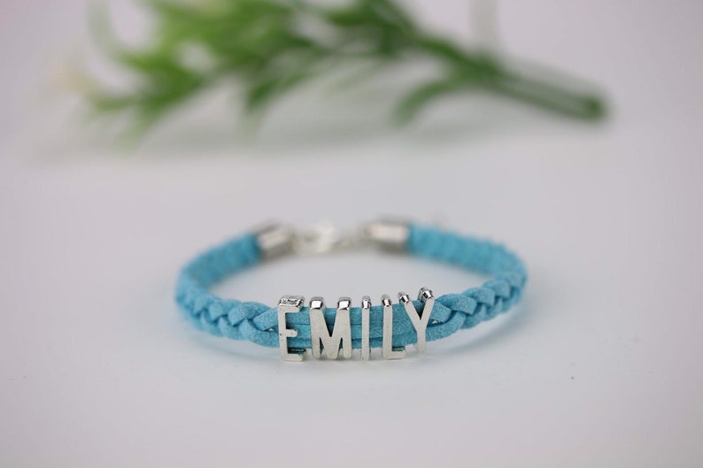 May include: A blue braided leather bracelet with a silver charm that says "EMILY".