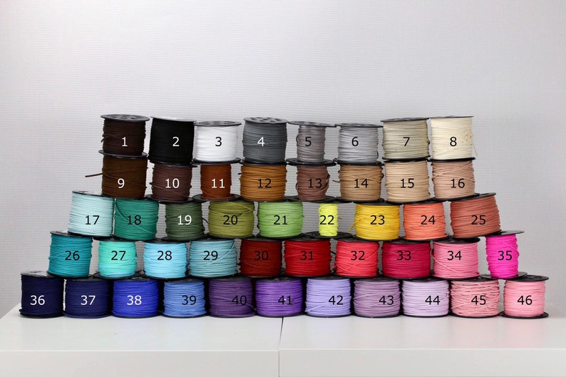 May include: A collection of 46 spools of thread, each wound with a different color of thread. The spools are arranged in a pyramid shape, with the numbers 1 through 46 printed on the front of each spool.