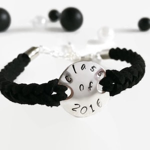May include: Black braided cord bracelet with a silver charm that says "Class of 2016".