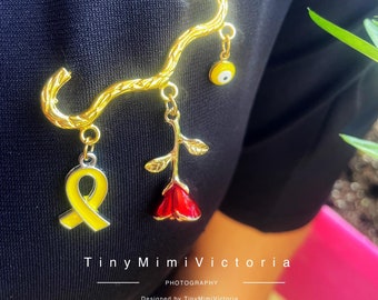 Broche bañado en oro: lazo amarillo, ojo malvado y rosa roja