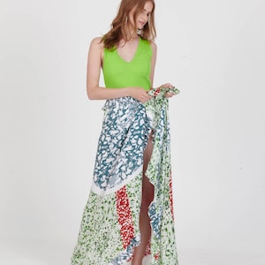 Op de afbeelding: Een mouwloze limoengroene top en een lange, bedrukte rok. De rok heeft witte, blauwgroene, rode en groene patronen. De outfit wordt gecompleteerd met witte espadrilles. De rok is ongeveer 100 cm lang.