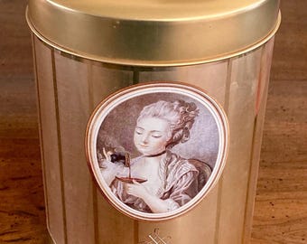 May include: A gold-colored Savoy Coffee tin with a matching lid. The tin features a vertical striped pattern and a central oval image of a woman pouring coffee. The words "Savoy Coffee" are printed on the front.