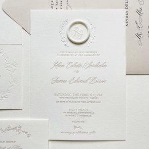May include: Elegant wedding invitation suite in cream with embossed floral details. The invitation features a wax seal with initials and script text announcing the marriage of Rhea Celeste Sardinha and James Edward Brown.