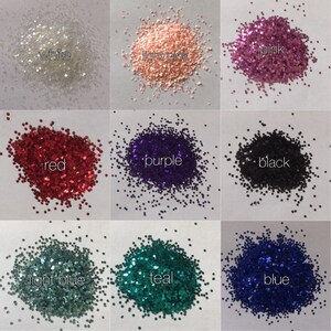 Op de afbeelding: Negen kleine stapeltjes glitter in verschillende kleuren: wit, lichtroze, roze, rood, paars, zwart, lichtblauw, teal en blauw.