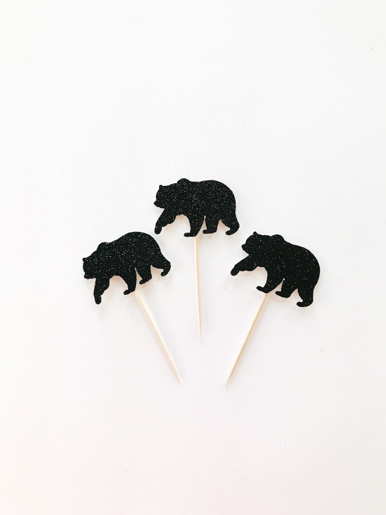 May include: Three black glitter bear cupcake toppers on white sticks. The bears are walking in a silhouette style.
