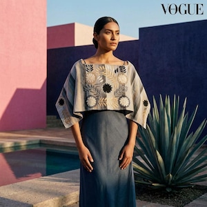 May include: A two-piece outfit consisting of a cropped, wide-sleeve top and a matching floor-length skirt. The top features a light gray base with vertical stripes and intricate floral embroidery in white, beige, and black. The skirt is solid gray.