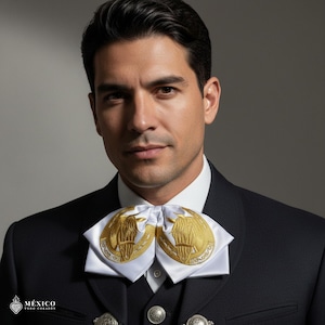 May include: A formal black suit with a white shirt and a decorative white bow tie featuring gold embroidery. The bow tie has a symmetrical design with two gold emblems. The image includes the text "MÉXICO TODO CORAZÓN".