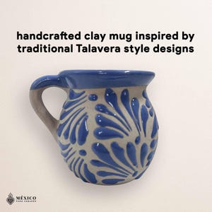 Peut inclure: Mug en argile fait &agrave; la main avec un bord et une anse bleus, inspir&eacute; des motifs de Talavera. Le mug pr&eacute;sente une base gris clair avec des motifs floraux bleus. Le texte de l'image indique : "mug en argile fait &agrave; la main inspir&eacute; des motifs Talavera".