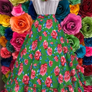 May include: A green skirt with a pink rose print and a ruffled hem. The skirt is made of a lightweight fabric and is perfect for a summer party or a casual day out.