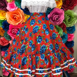 Puede incluir: Una falda roja con estampado floral azul y ribete blanco. La falda es amplia y tiene una cintura fruncida. Est&aacute; hecha de una tela ligera y es perfecta para una ocasi&oacute;n especial.