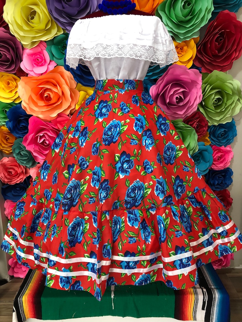 Puede incluir: Una falda roja con estampado floral azul y ribete blanco. La falda es amplia y tiene una cintura fruncida. Est&aacute; hecha de una tela ligera y es perfecta para una ocasi&oacute;n especial.