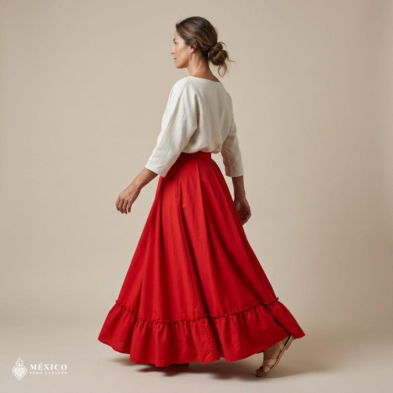 May include: A long, vibrant red skirt featuring a gathered ruffle hemline, paired with a cream-colored, three-quarter sleeve top. The skirt has a full, flowing silhouette that reaches the ankles, while the top has a simple, round neckline.