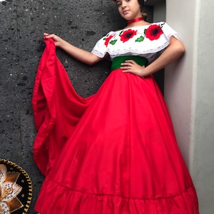 May include: A white off-the-shoulder blouse with red poppy floral embroidery and lace trim, paired with a wide green sash and a long, voluminous red skirt with a ruffled hem. A red floral headpiece and a red choker complete the ensemble.