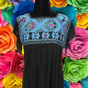 May include: Black embroidered dress with a blue and multi-colored geometric pattern on the neckline. The dress has a loose fit and a simple design.