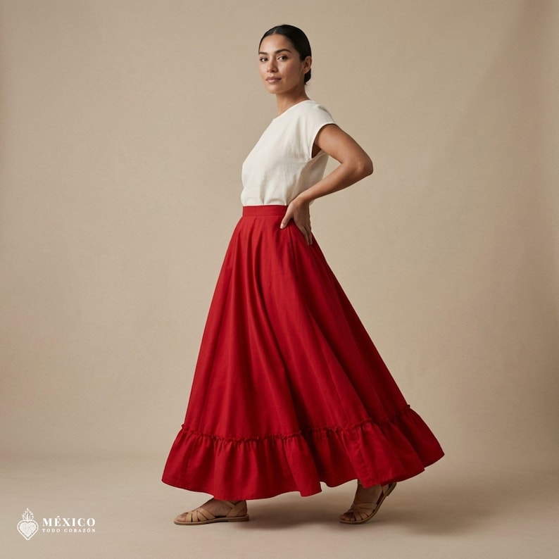May include: A solid red ankle-length skirt featuring a gathered ruffle hemline, paired with a plain white short-sleeved top. The skirt has a high waistband and a full, flowing silhouette. The text "M&Eacute;XICO TODO CORAZ&Oacute;N" appears in the bottom corner.