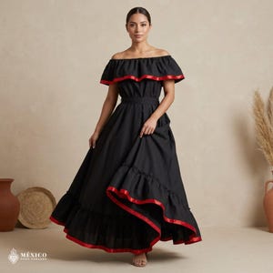 May include: A black off-the-shoulder maxi dress featuring a wide ruffled neckline and a tiered skirt, both accented with a vibrant red ribbon trim. The dress includes a fitted waist and a long, flowing skirt that reaches the floor.