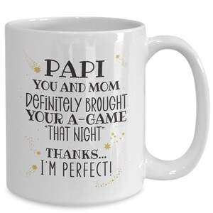 May include: White ceramic mug with the text "PAPI YOU AND MOM DEFINITELY BROUGHT YOUR A-GAME 'THAT NIGHT' THANKS... I'M PERFECT!" in black lettering. Gold star and comet accents are also present.