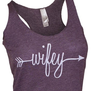 May include: A purple tank top with a white arrow and the word "wifey" printed on the front.