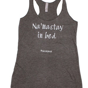 Puede incluir: Camiseta de tirantes gris con el texto "Na'masstay in bed #savasana" en blanco.