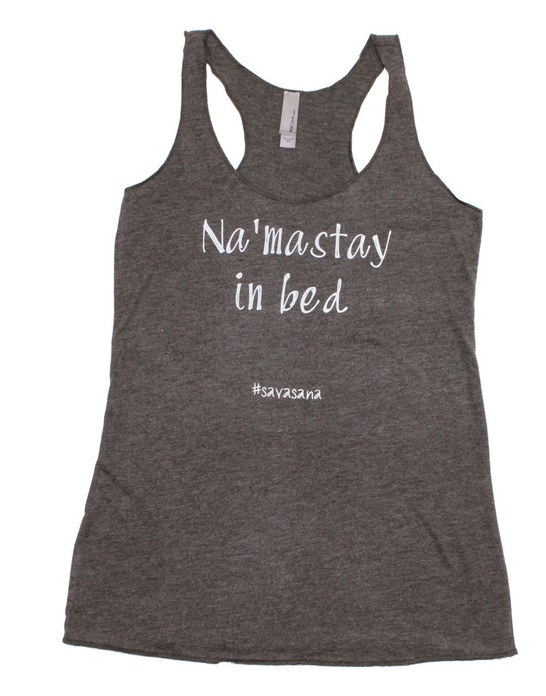 Puede incluir: Camiseta de tirantes gris con el texto "Na'masstay in bed #savasana" en blanco.