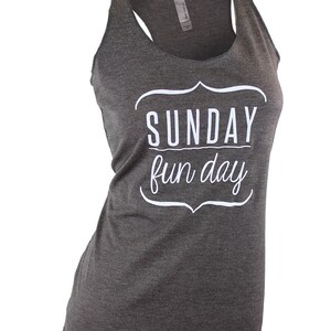 Op de afbeelding: Een grijs tanktop met een witte afbeelding die "SUNDAY fun day" zegt in een decoratief lettertype.