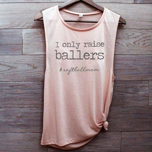 May include: A peach-colored sleeveless shirt with the text "I only raise ballers #softballmom" printed on the front.