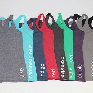 May include: A row of ten racerback tank tops in various colors, including gray, caribbean blue, indigo, red, espresso, kelly green, purple, mocha, and black.