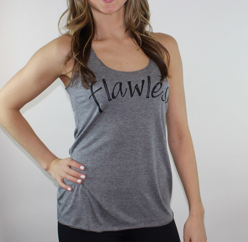 May include: Gray tank top with the word "flawless" written in black cursive script.