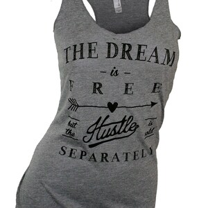 May include: Gray tank top with a black graphic that reads "The Dream -is- Free but the Hustle is sold separately".