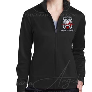 May include: A black zip-up jacket featuring an embroidered graphic on the left chest. The design displays a white rib cage, the word Radiology, a red heart, a red EKG line, and the text Angela R.T. (R)(CT) printed in white lettering.
